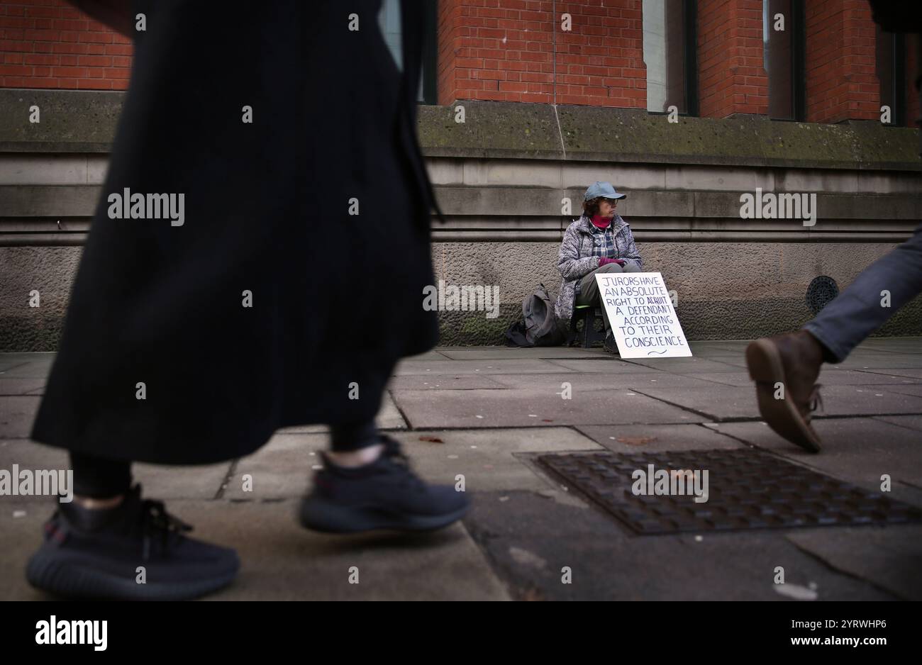 Members of the public stride past the sitters. Protesters sit silently ...