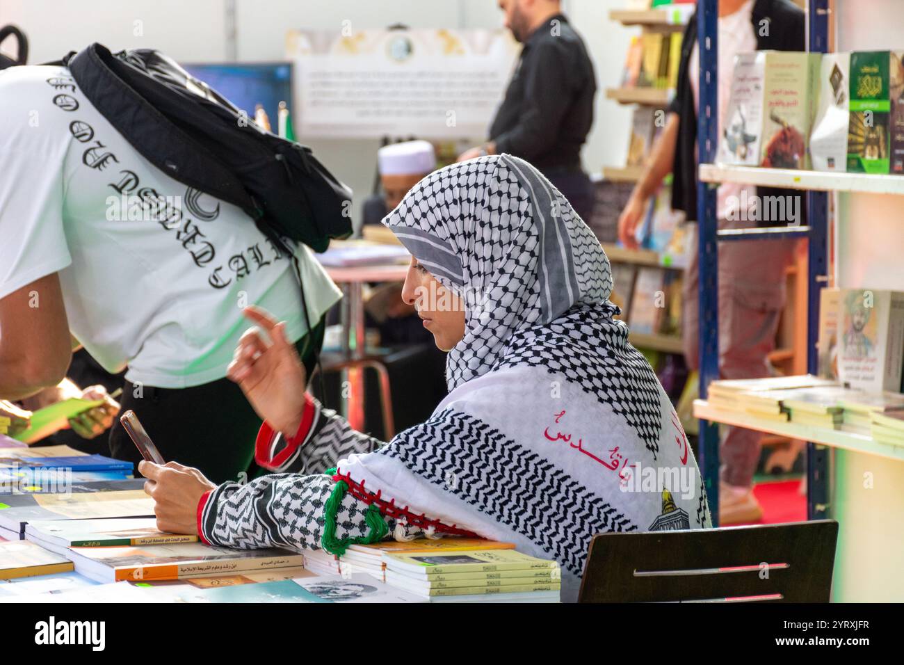 A female publisher wearing kufiya at Algiers International Book Fair 2024, Algeria. Stock Photo