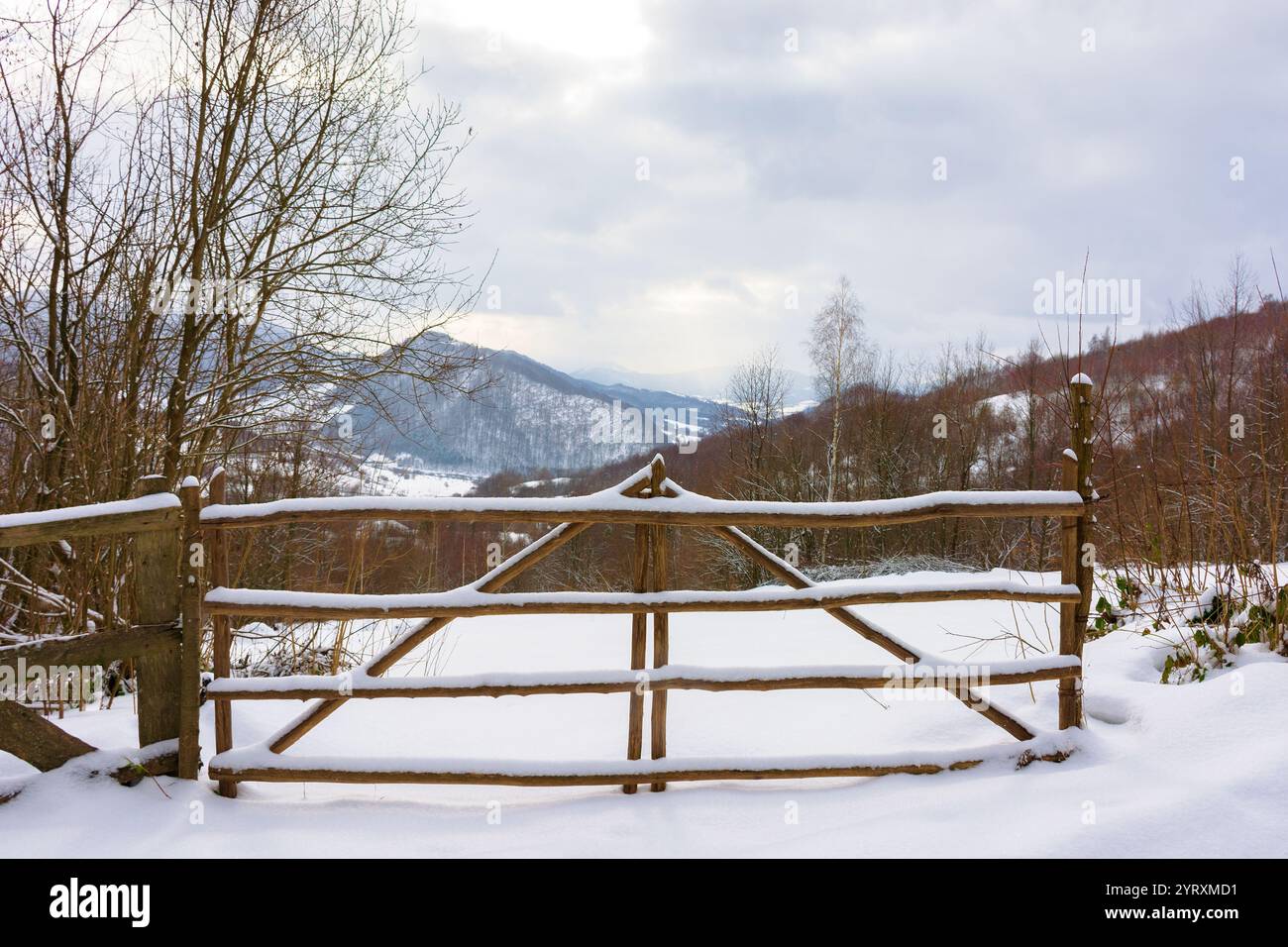 countryside landscape in winter. retro construction. wooden fence through snow covered hill. outdoor adventure Stock Photo