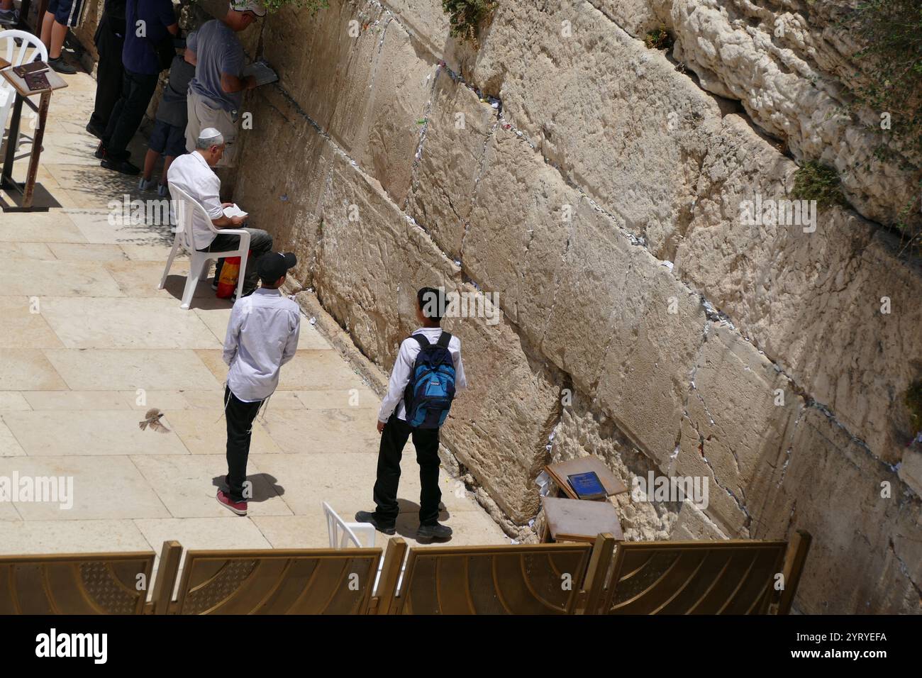 Jews pray at the Western Wall, (Wailing Wall, or Kotel), an ancient limestone wall in the Old City of Jerusalem. It is a relatively small segment of a far longer ancient retaining wall. The wall was originally erected as part of the expansion of the Second Jewish Temple begun by Herod the Great, Stock Photo