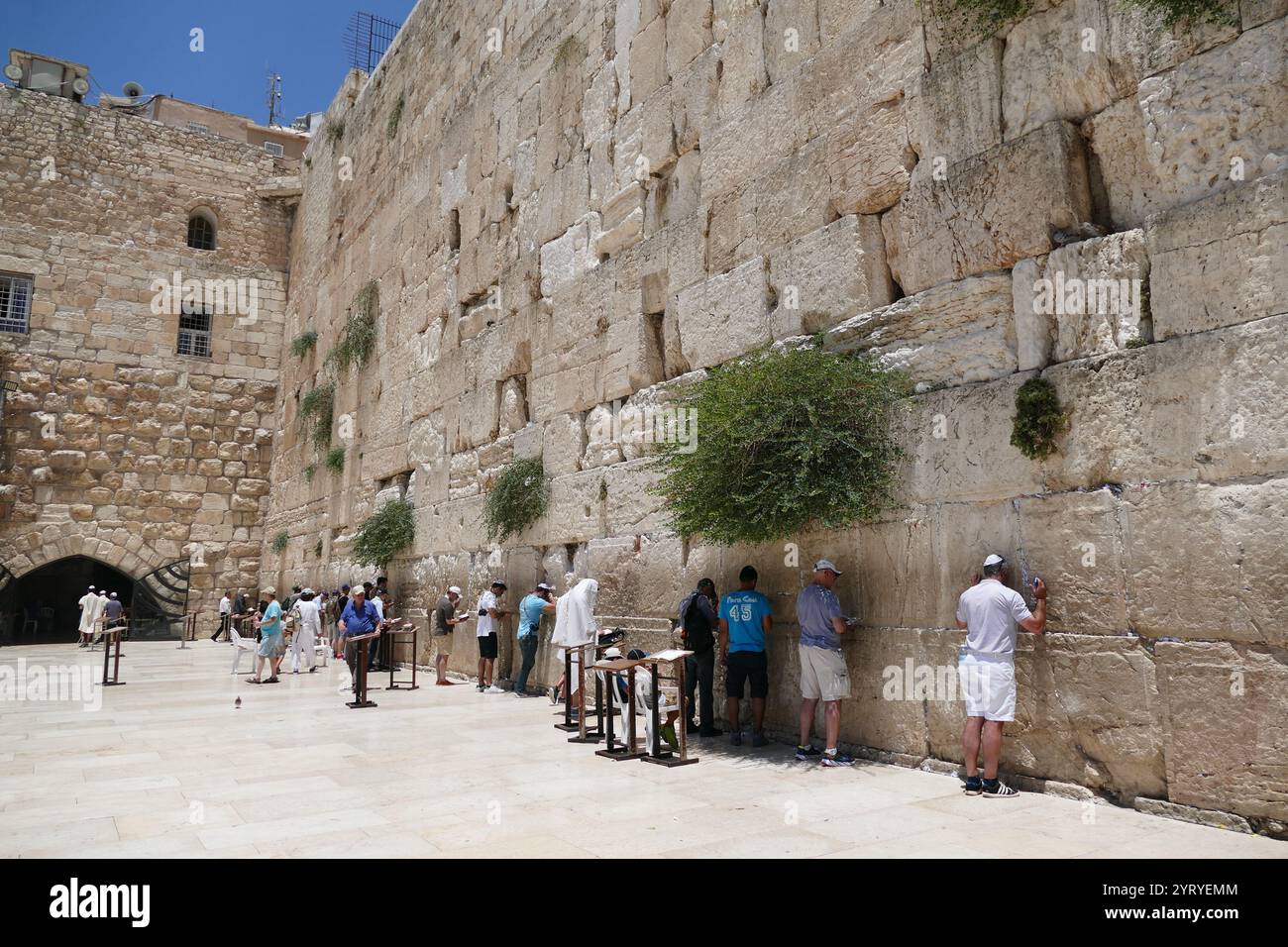 Jews pray at the Western Wall, (Wailing Wall, or Kotel), an ancient limestone wall in the Old City of Jerusalem. It is a relatively small segment of a far longer ancient retaining wall. The wall was originally erected as part of the expansion of the Second Jewish Temple begun by Herod the Great, Stock Photo