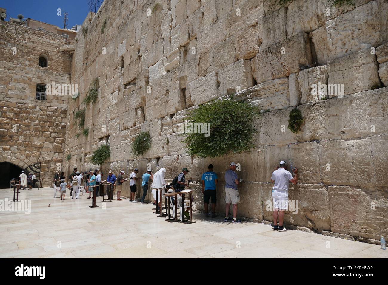 Jews pray at the Western Wall, (Wailing Wall, or Kotel), an ancient limestone wall in the Old City of Jerusalem. It is a relatively small segment of a far longer ancient retaining wall. The wall was originally erected as part of the expansion of the Second Jewish Temple begun by Herod the Great, Stock Photo