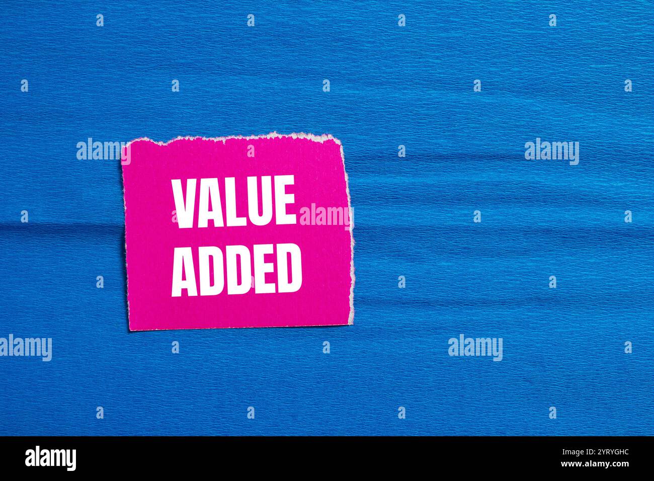 Value added message written on ripped pink torn paper piece with blue ...