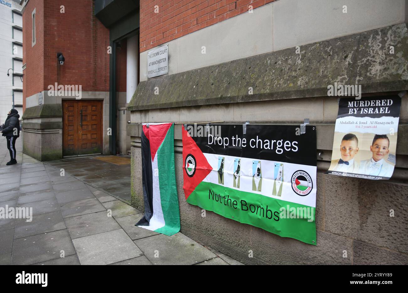 Manchester, UK. 04th Dec, 2024. A single protester stands outside court with banners and a flag fixed to the wall during the demonstration on the first day of the Ferranti 2 trial at Manchester Crown Court. During the demonstration, supporters of the Ferranti 2 protested outside Manchester Crown Court as the trial begins. Their action and sustained local support led to Elbit Systems closing the Ferranti factory in Oldham in January 2022. Credit: SOPA Images Limited/Alamy Live News Stock Photo