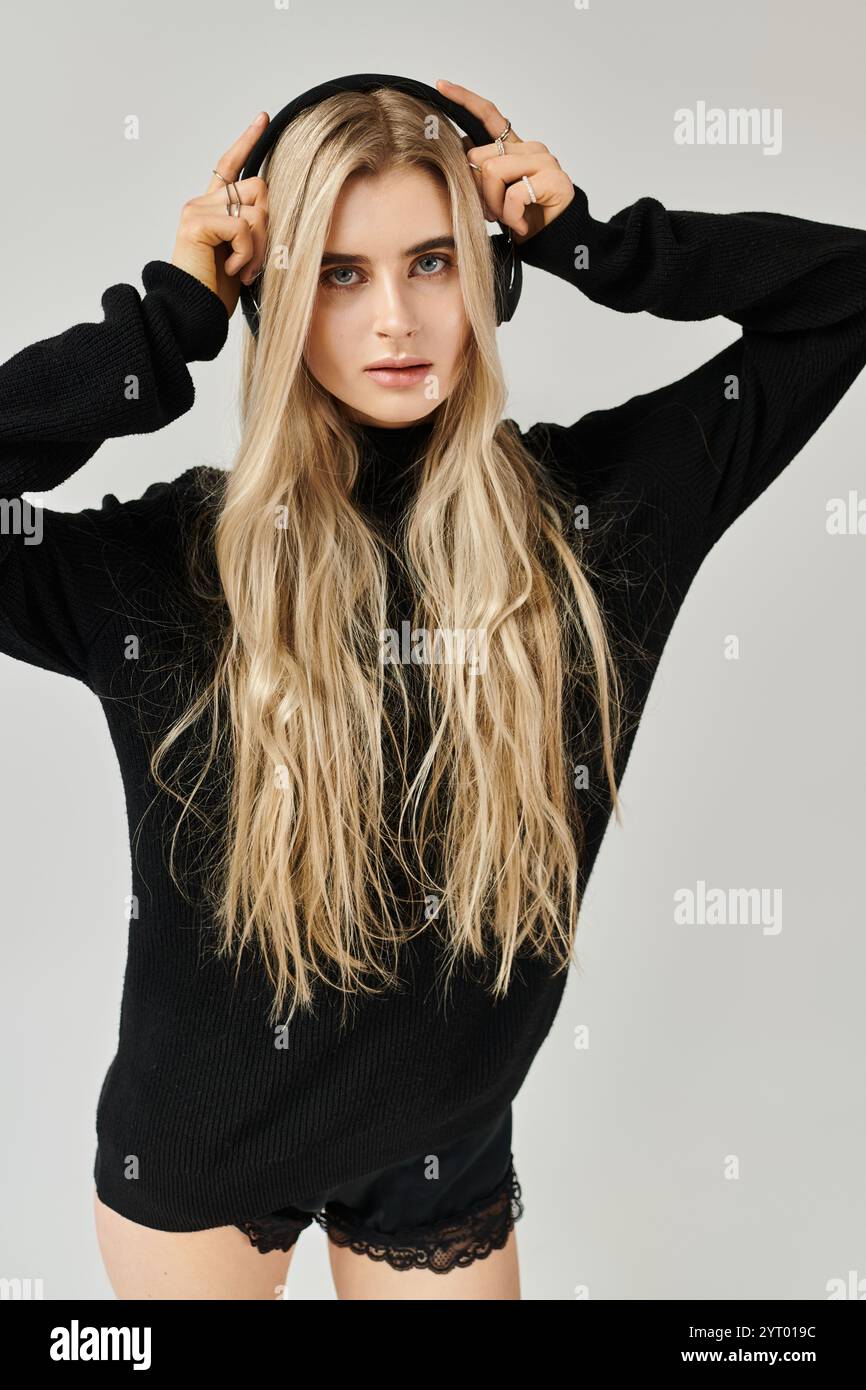 Blonde woman with long hair poses confidently in a black outfit ...