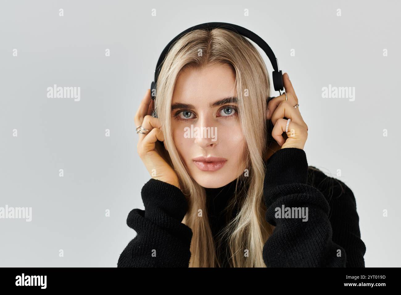 A beautiful young woman with long blonde hair is posing with headphones ...