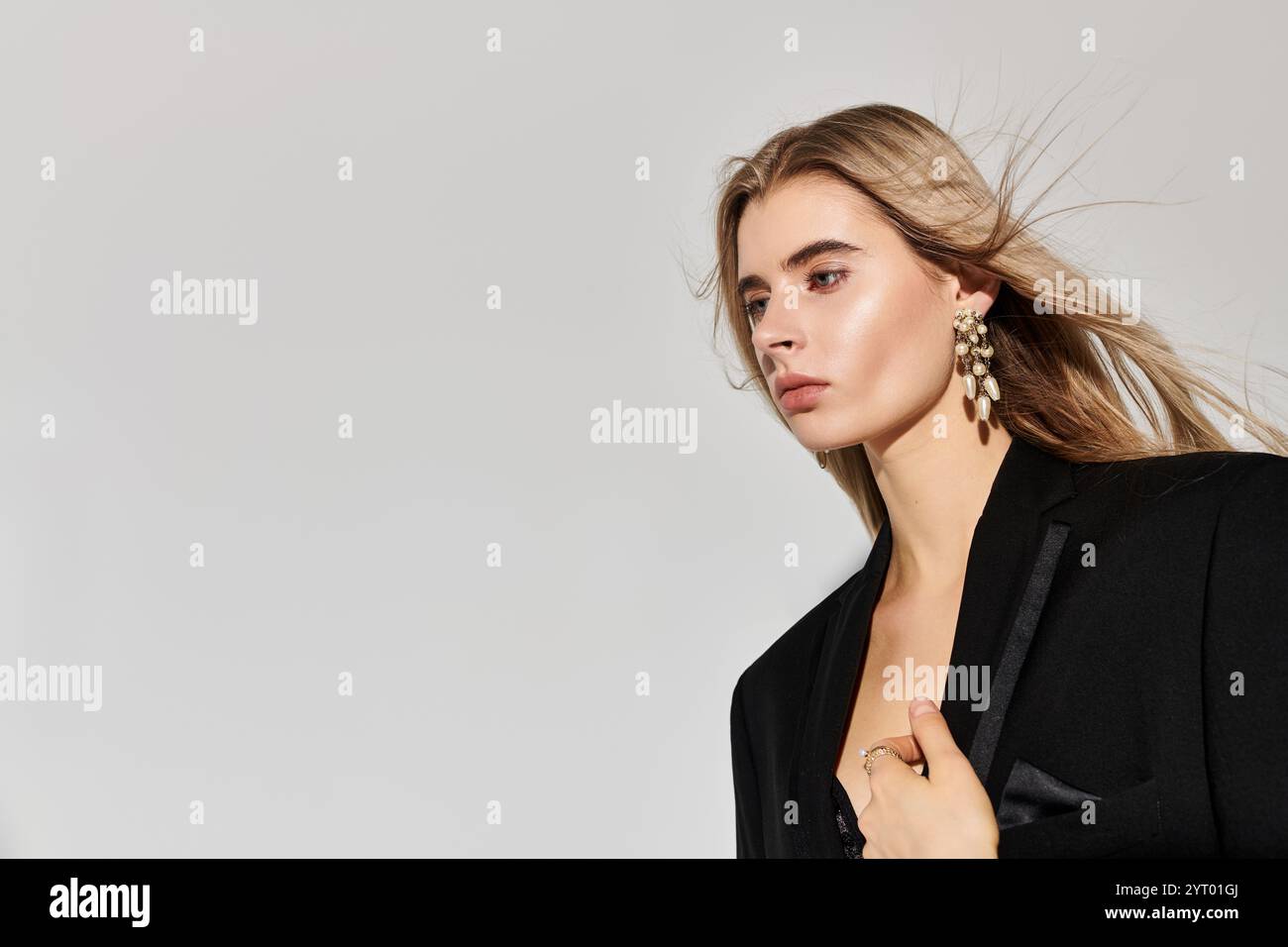 A confident young woman with long blonde hair poses elegantly in a chic ...