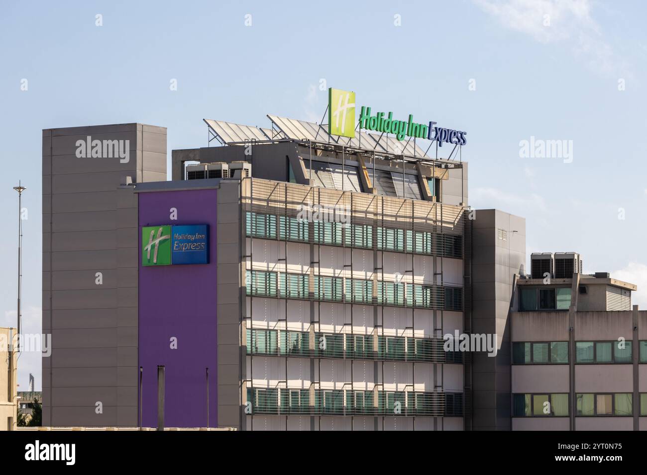 Modern hotel building with prominent holiday inn express branding and rooftop solar panels, demonstrating sustainable practices in the hospitality ind Stock Photo