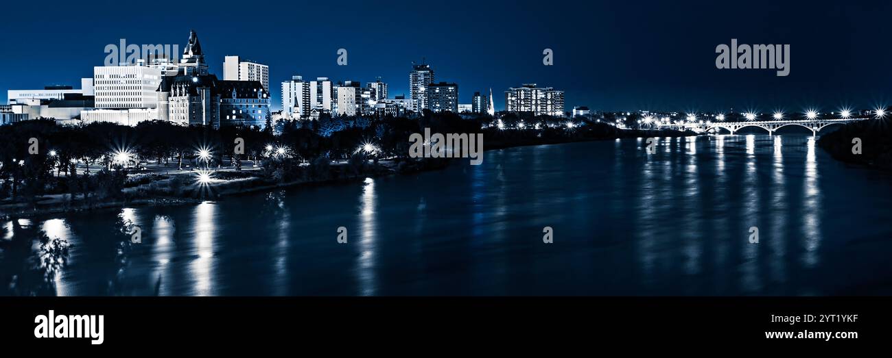 A city skyline is lit up at night, with the river reflecting the lights. Scene is serene and peaceful, as the city and river come together to create a Stock Photo
