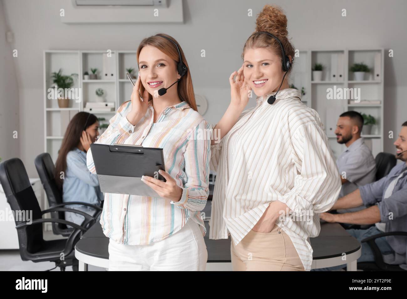 Female technical support agents with headsets and clipboard in office ...
