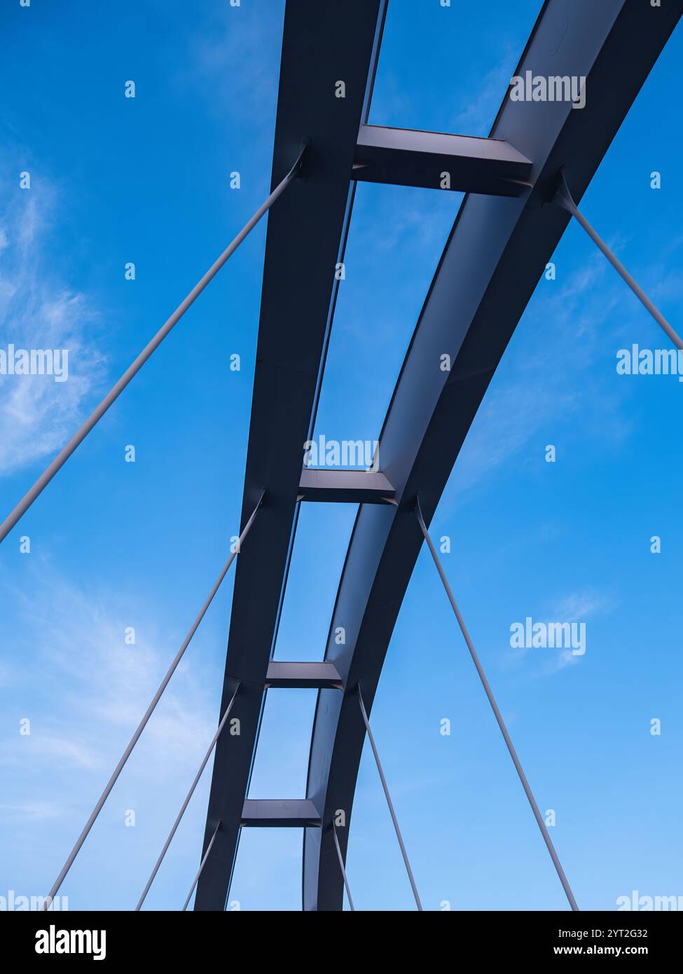 Stockholm, Sweden - 24 May 2024: A sleek, modern bridge showcases a dynamic steel arch and cables against a bright blue sky Stock Photo