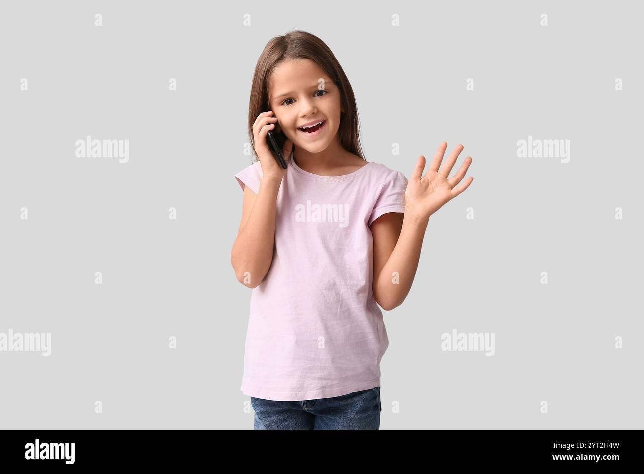 Happy little girl talking by phone on white background Stock Photo - Alamy