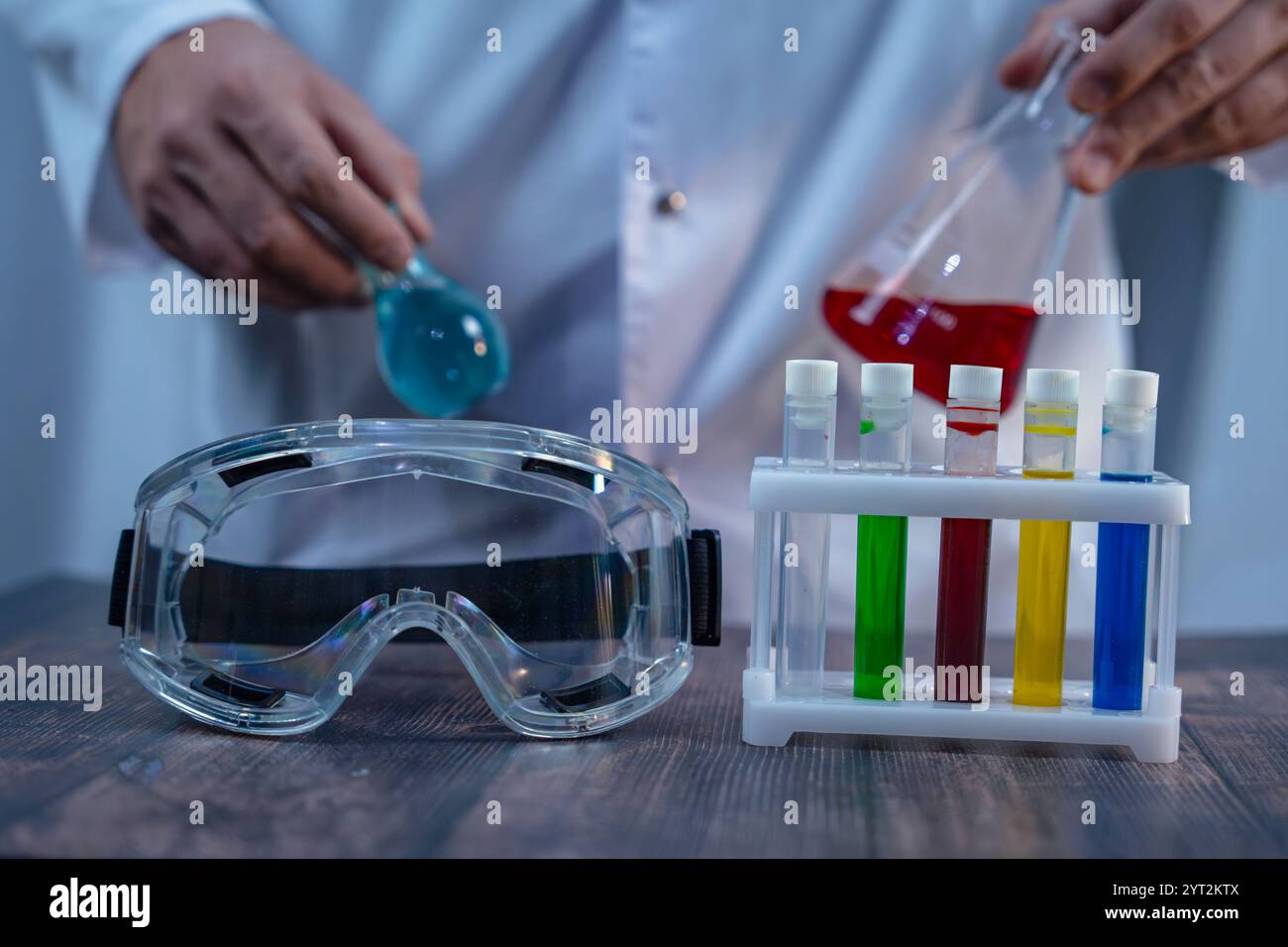 A laboratory setup featuring colorful test tubes, safety goggles, and ...