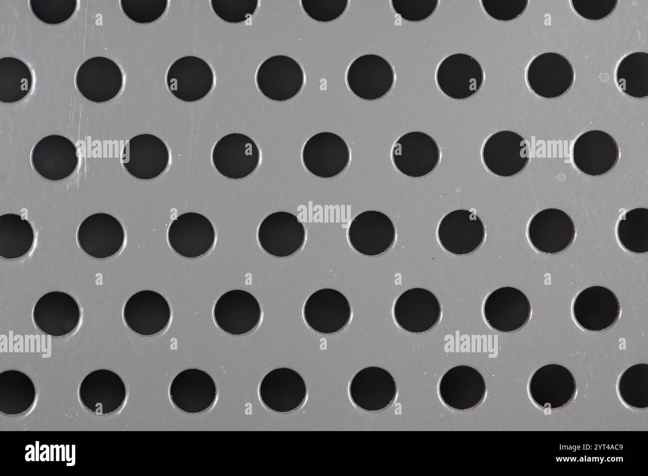 Perforations in a grey metal panel Stock Photo