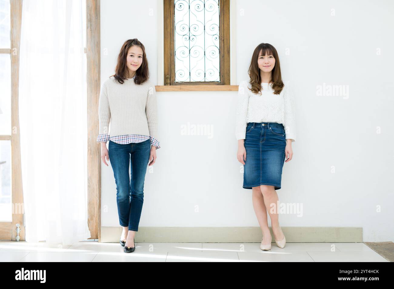Two young women standing in front of wall Stock Photo - Alamy