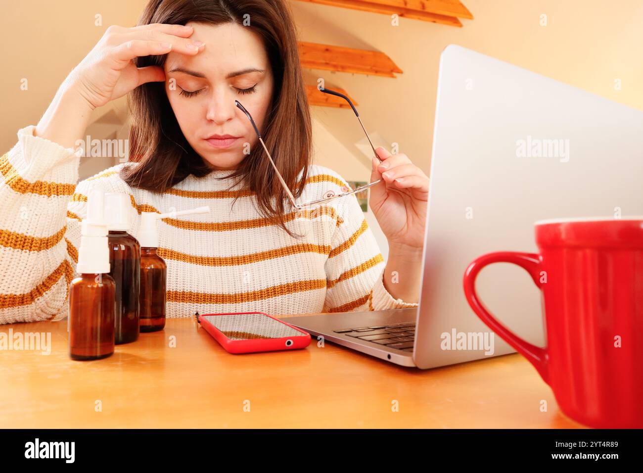 remote-work-with-a-woman-holding-glasses-and-medicine-2YT4R89.jpg