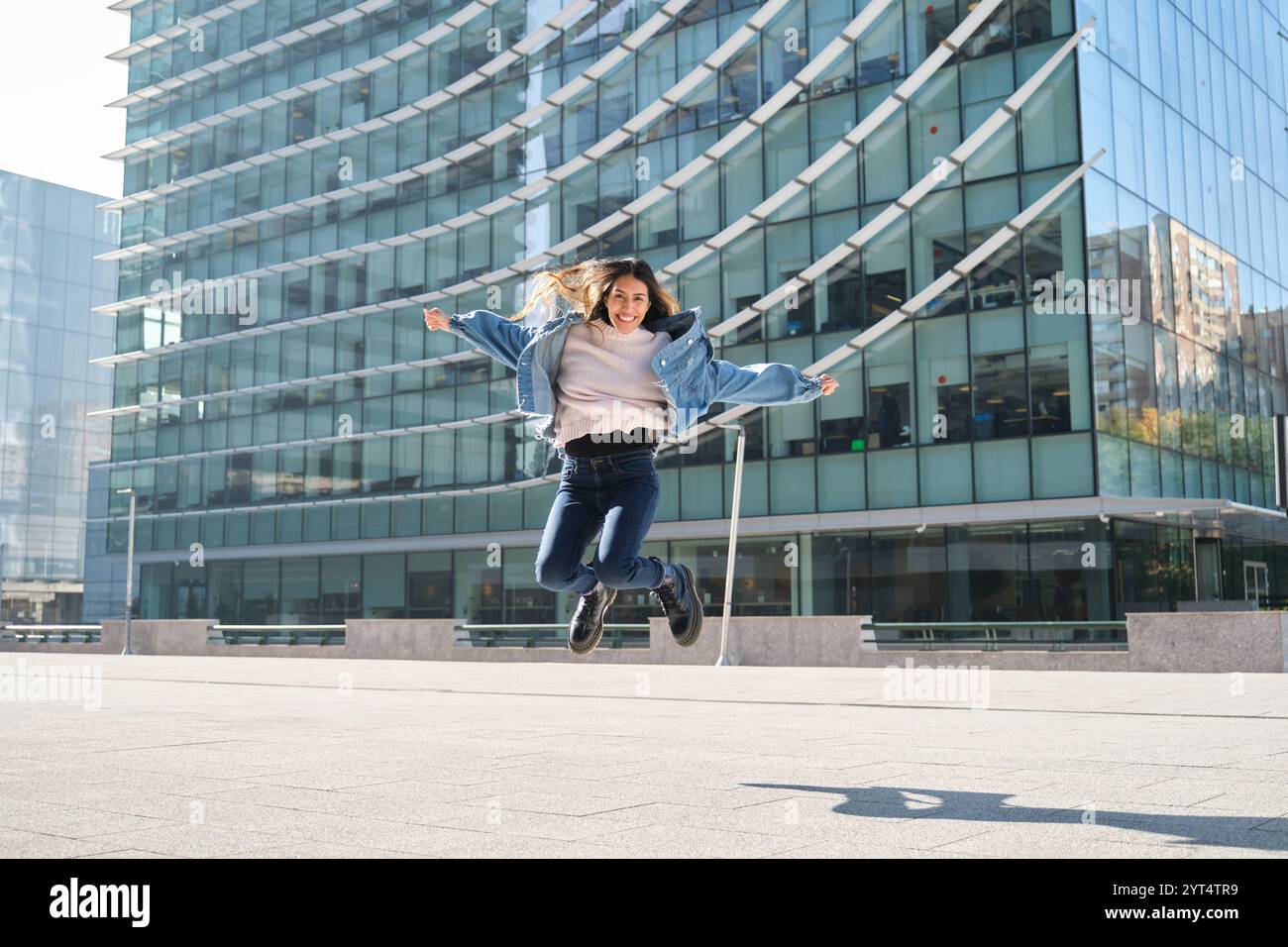 Young woman celebrating achievement jumping in front of a building Stock Photo