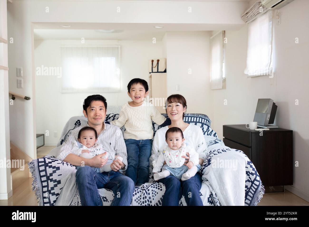 Family of five sitting on a sofa and smiling Stock Photo - Alamy