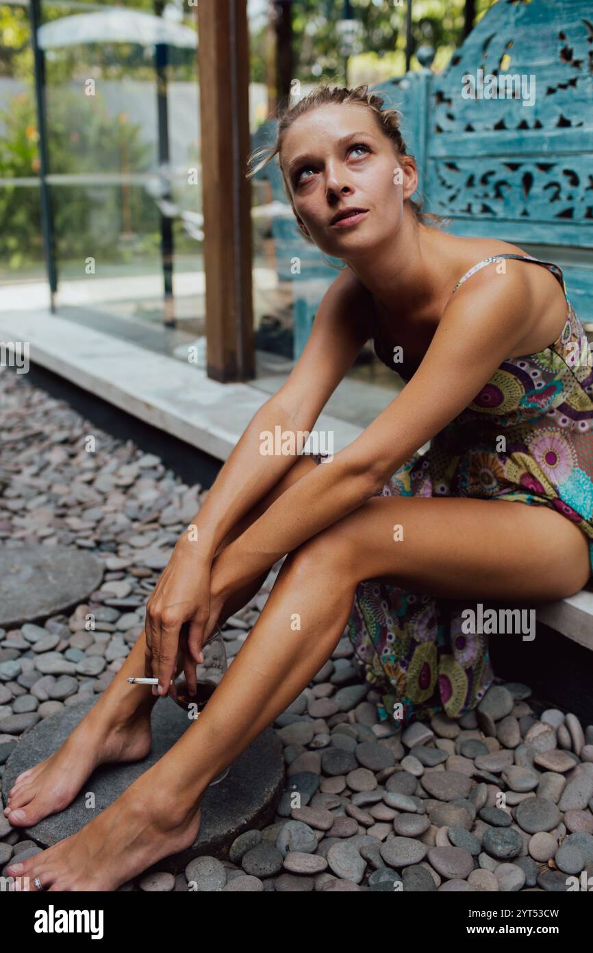 Young woman smoking cigarette sitting on backyard Stock Photo - Alamy