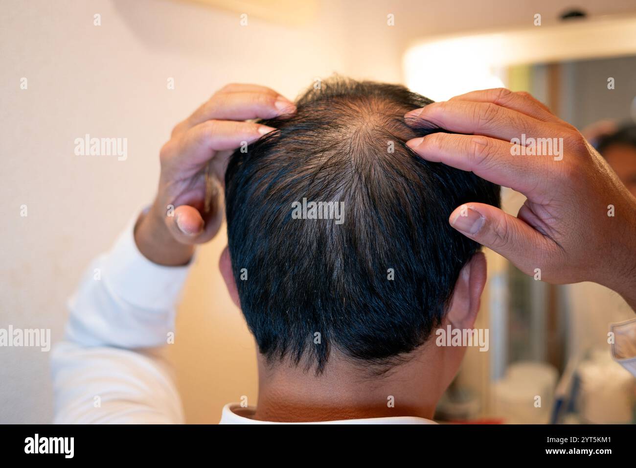 Man checks thinning hair in front of a bathroom mirror Stock Photo Alamy