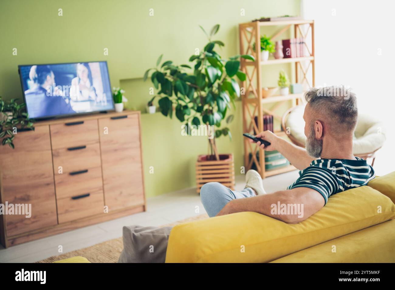 Elderly man relaxing at home watching television in cozy living room setting Stock Photo