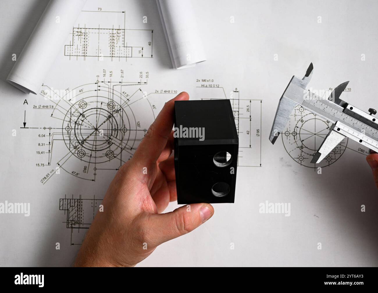 Engineer comparing a plastic component with its technical drawing using ...