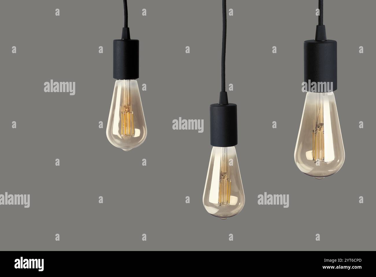 Three light bulbs hanging on grey background Stock Photo