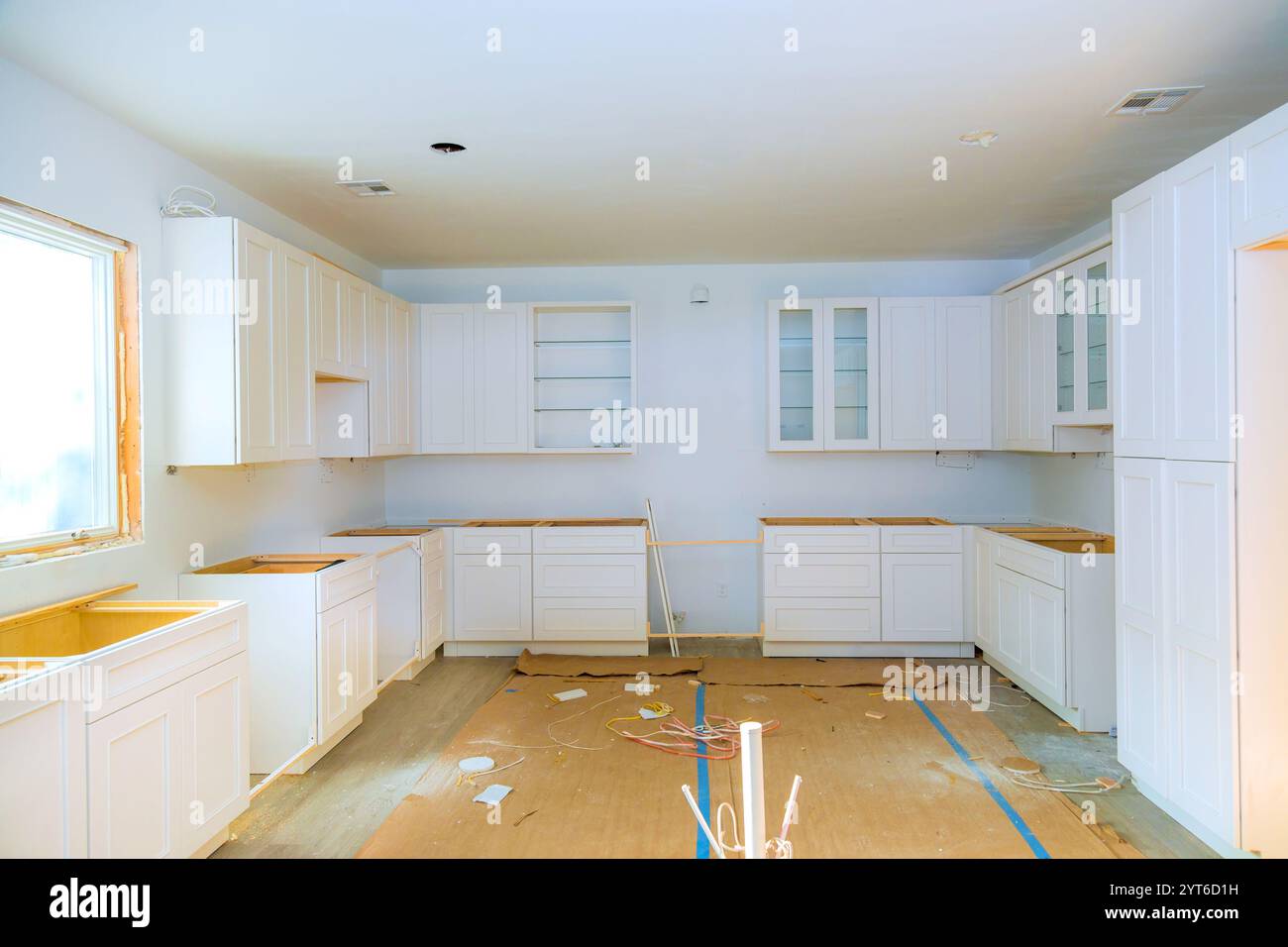 Brightly lit kitchen undergoing renovation with white cabinets ...