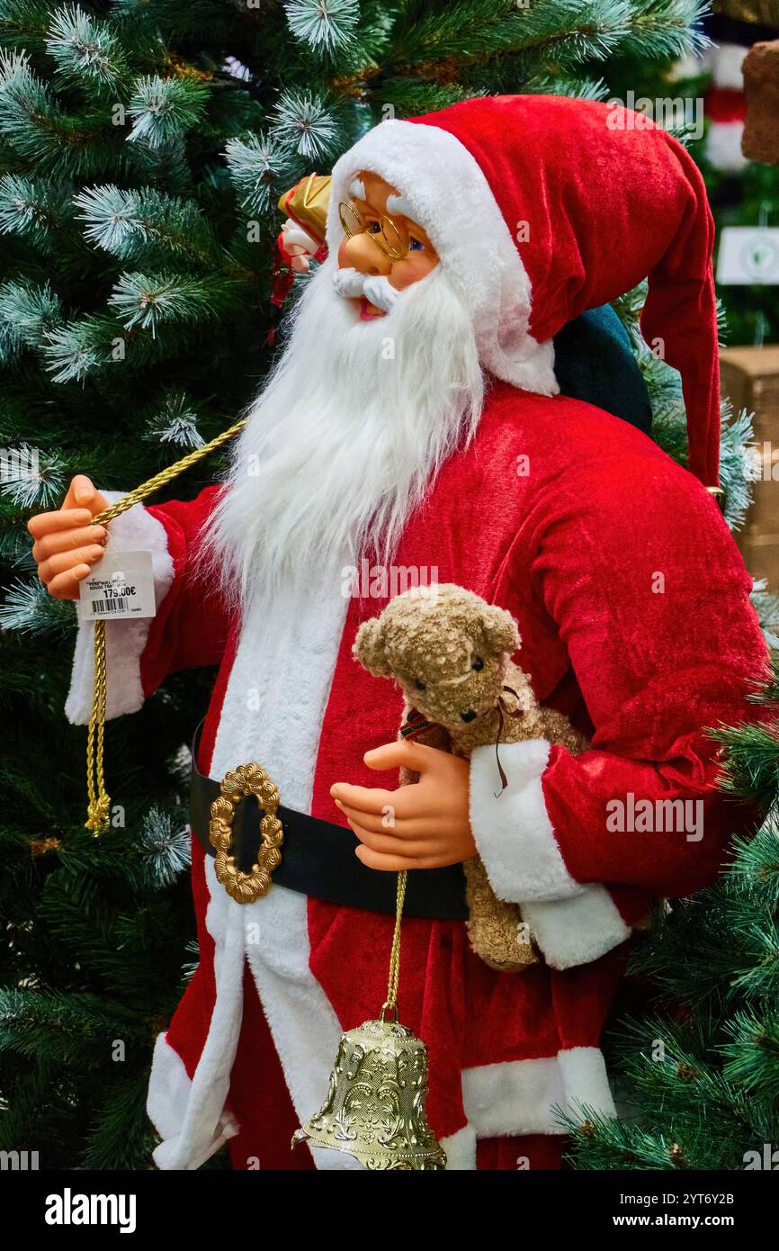 Santa Claus Figurine with Teddy Bear and Bell Under Christmas Tree Stock Photo