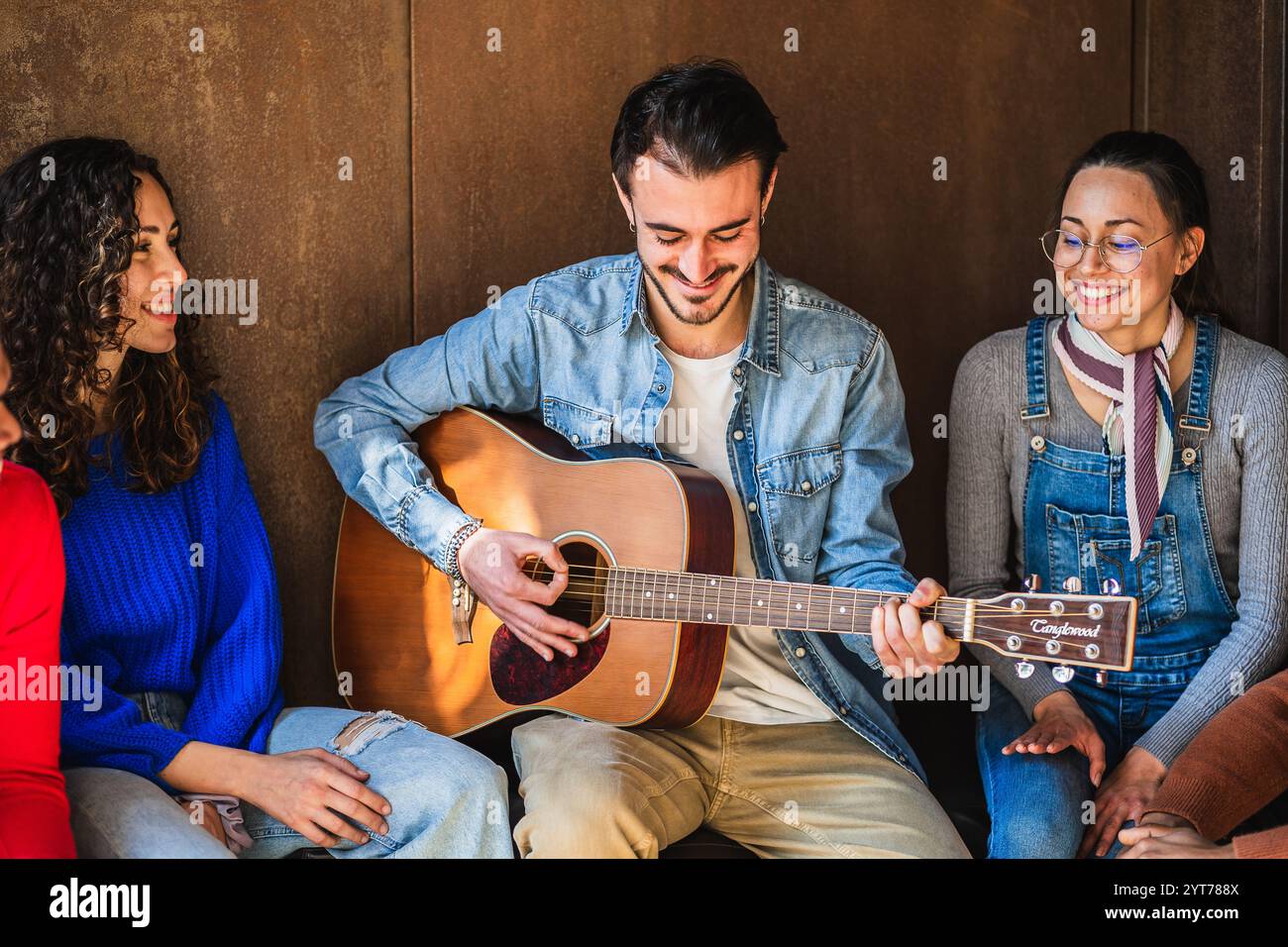 Young musician playing acoustic guitar and entertaining his friends Stock Photo