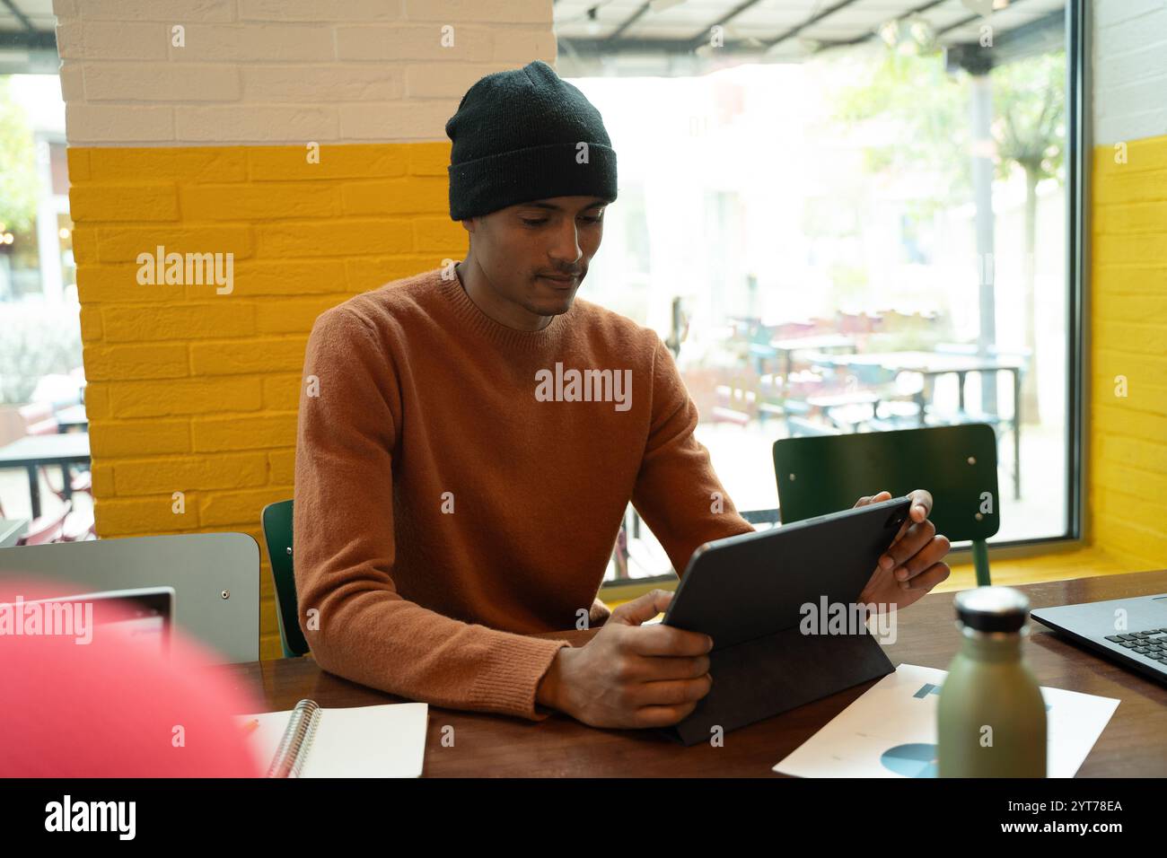 Focused young businessman using digital tablet while working remotely in cafe Stock Photo