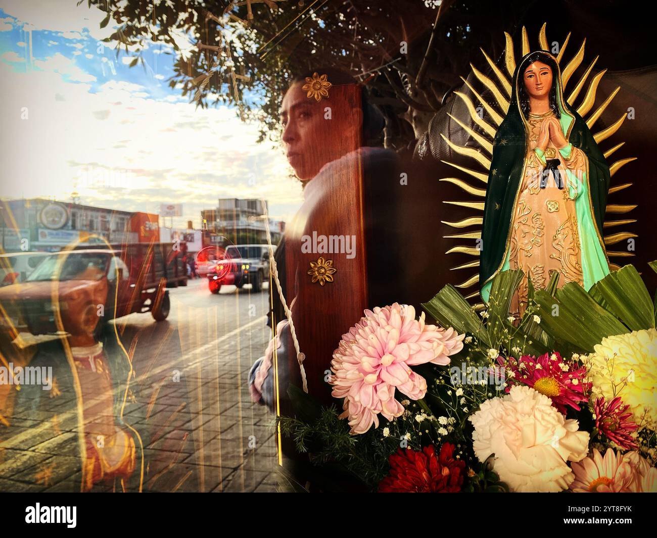 A woman´s reflection in an altar to Our Lady of Guadalupe as she waits for a taxi in the streets of Ezequiel Montes, Queretaro, Mexico - Smartphone Captured Stock Image