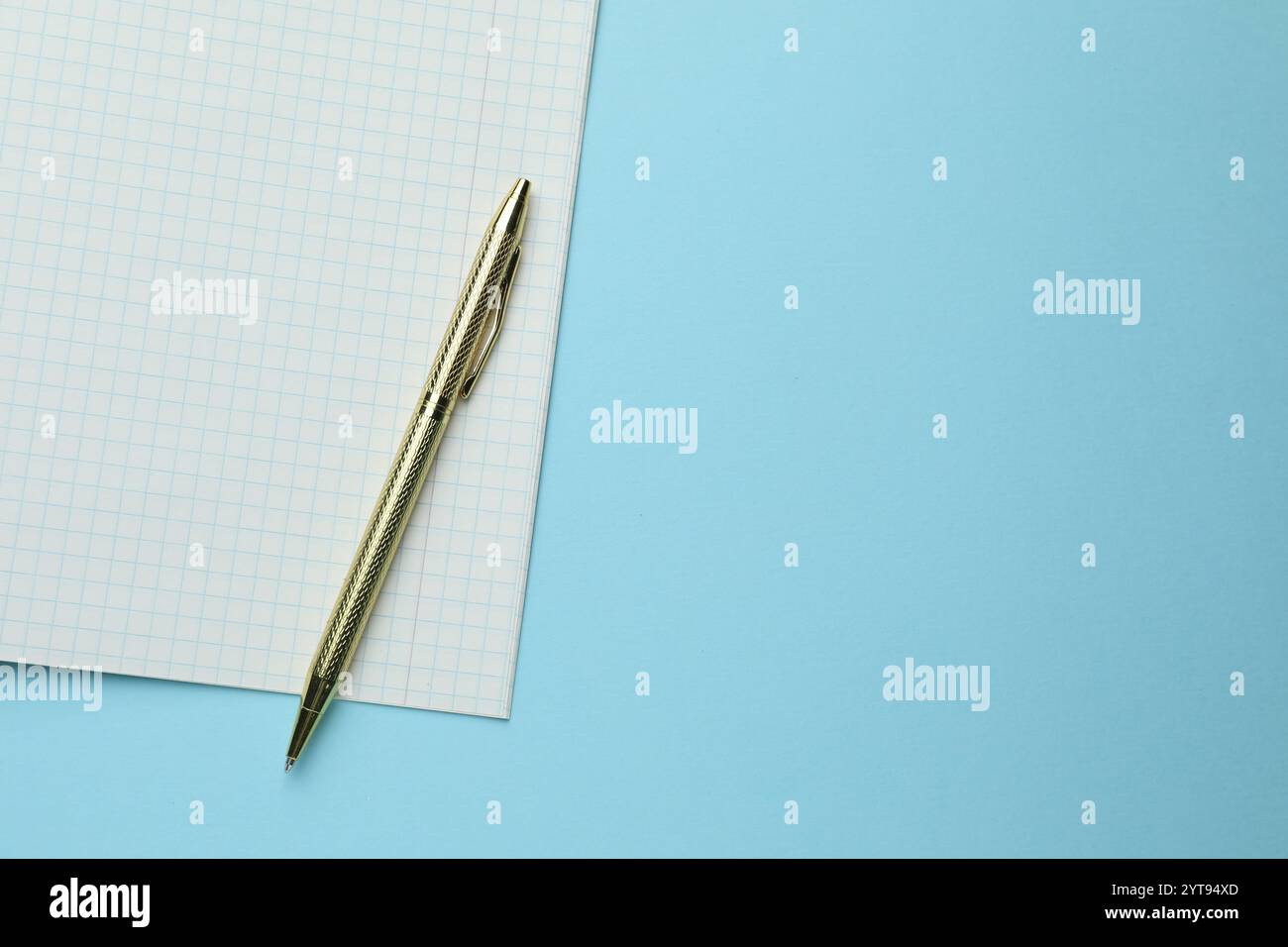 Open copybook and pen on light blue background, top view. Space for ...
