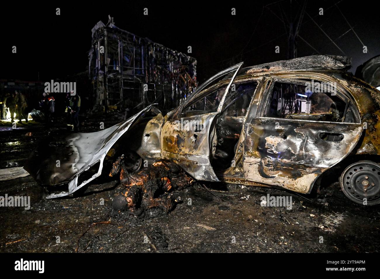 ZAPORIZHZHIA, UKRAINE - DECEMBER 6, 2024 - A burnt body is on the ground by a calcinated car after a Russian air strike, Zaporizhzhia, southeastern Ukraine. On Friday evening, the Russian military carried out two strikes on Zaporizhzhia and Zaporizhzhia district. The first strike that targeted a residential area in the regional centre destroyed a car repair shop and damaged nearby homes and shops. At least ten people were killed and 22 people got injured. The second strike hit an open area in Zaporizhzhia district. According to the Zaporizhzhia Regional Police, Russian troops attacked the city Stock Photo