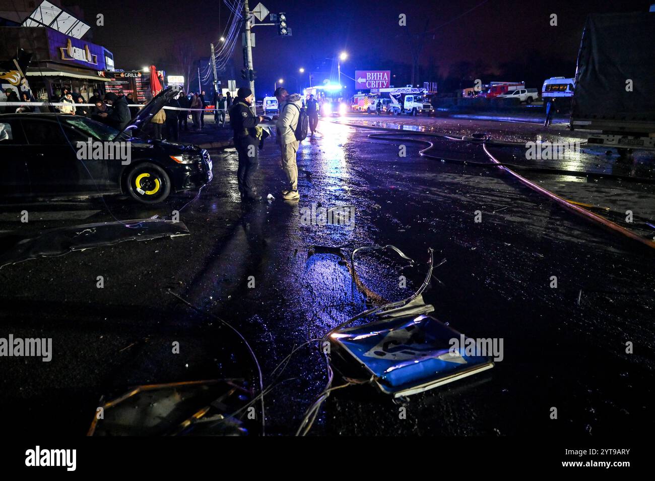 ZAPORIZHZHIA, UKRAINE - DECEMBER 6, 2024 - People are at the scene of a Russian air strike, Zaporizhzhia, southeastern Ukraine. On Friday evening, the Russian military carried out two strikes on Zaporizhzhia and Zaporizhzhia district. The first strike that targeted a residential area in the regional centre destroyed a car repair shop and damaged nearby homes and shops. At least ten people were killed and 22 people got injured. The second strike hit an open area in Zaporizhzhia district. According to the Zaporizhzhia Regional Police, Russian troops attacked the city with FAB-250 bombs with UMPC Stock Photo