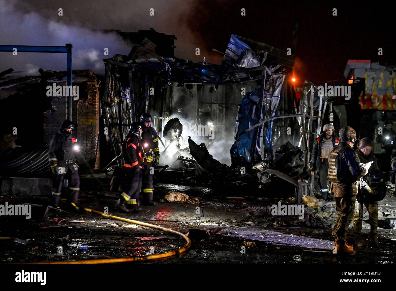 ZAPORIZHZHIA, UKRAINE - DECEMBER 6, 2024 - First responders deal with the consequences of a Russian air strike, Zaporizhzhia, southeastern Ukraine. On Friday evening, the Russian military carried out two strikes on Zaporizhzhia and Zaporizhzhia district. The first strike that targeted a residential area in the regional centre destroyed a car repair shop and damaged nearby homes and shops. At least ten people were killed and 22 people got injured. The second strike hit an open area in Zaporizhzhia district. According to the Zaporizhzhia Regional Police, Russian troops attacked the city with FAB Stock Photo