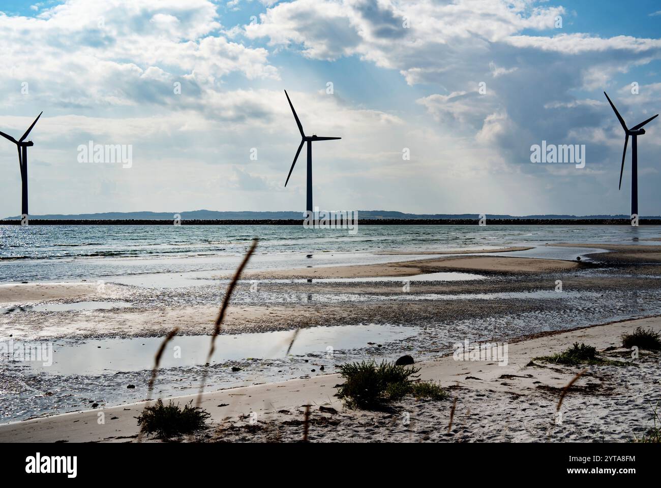 Wind turbine by the sea with glittering sunshine sun and blue sky ...