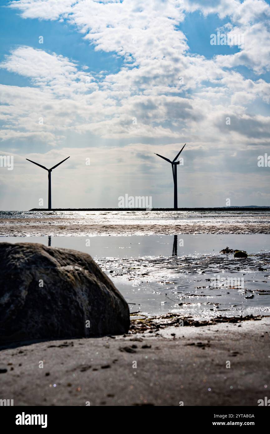 Wind turbine by the sea with glittering sunshine sun and blue sky ...
