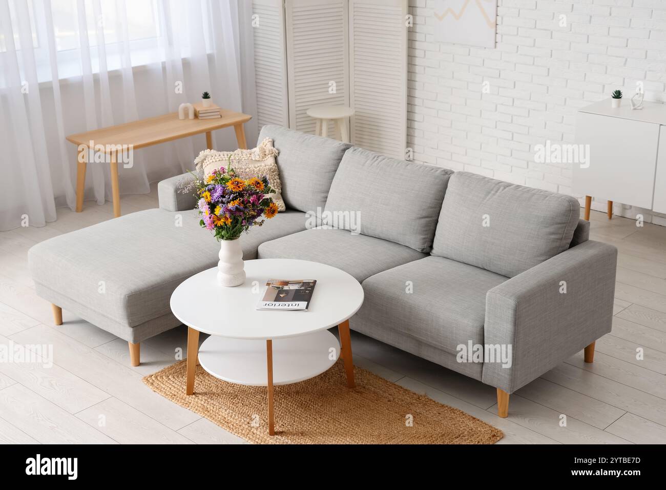 Cozy sofa and vase with wild flowers on coffee table in interior of ...