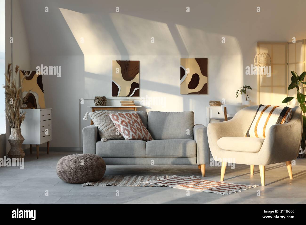 Cozy sofa, armchair and pictures in interior of living room Stock Photo ...