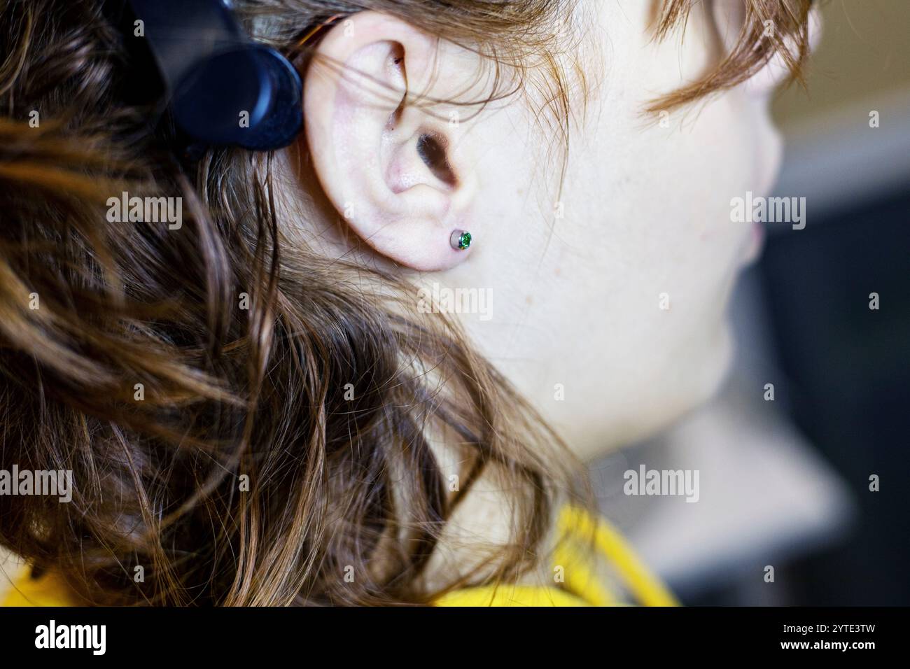 cosmetologist puts on a healing earring with a special tool. ear piercing. Style and beauty Stock Photo
