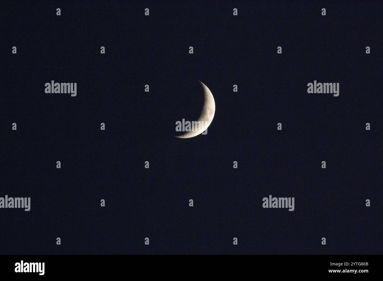 Crescent moon against a black night sky Stock Photo