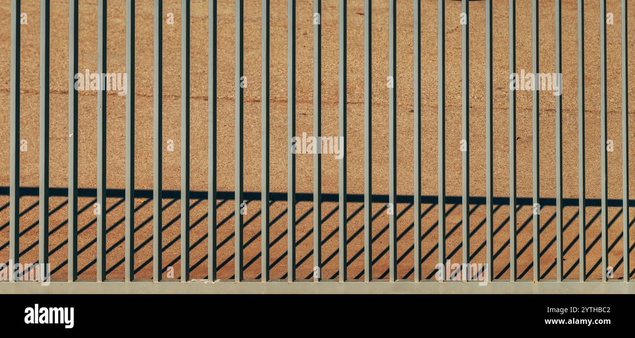 Steel bar fence forming unique pattern of light and shadow as industrial background, selective focus Stock Photo