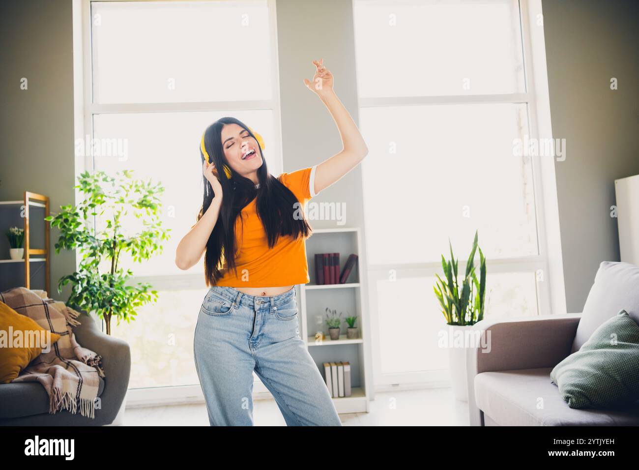 Joyful young woman dancing in living room enjoying music and bright ...