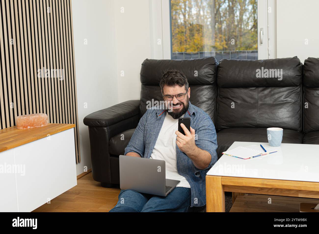 Angry stressed man having a phone call with a burnout face expression while working at the home office. Stock Photo
