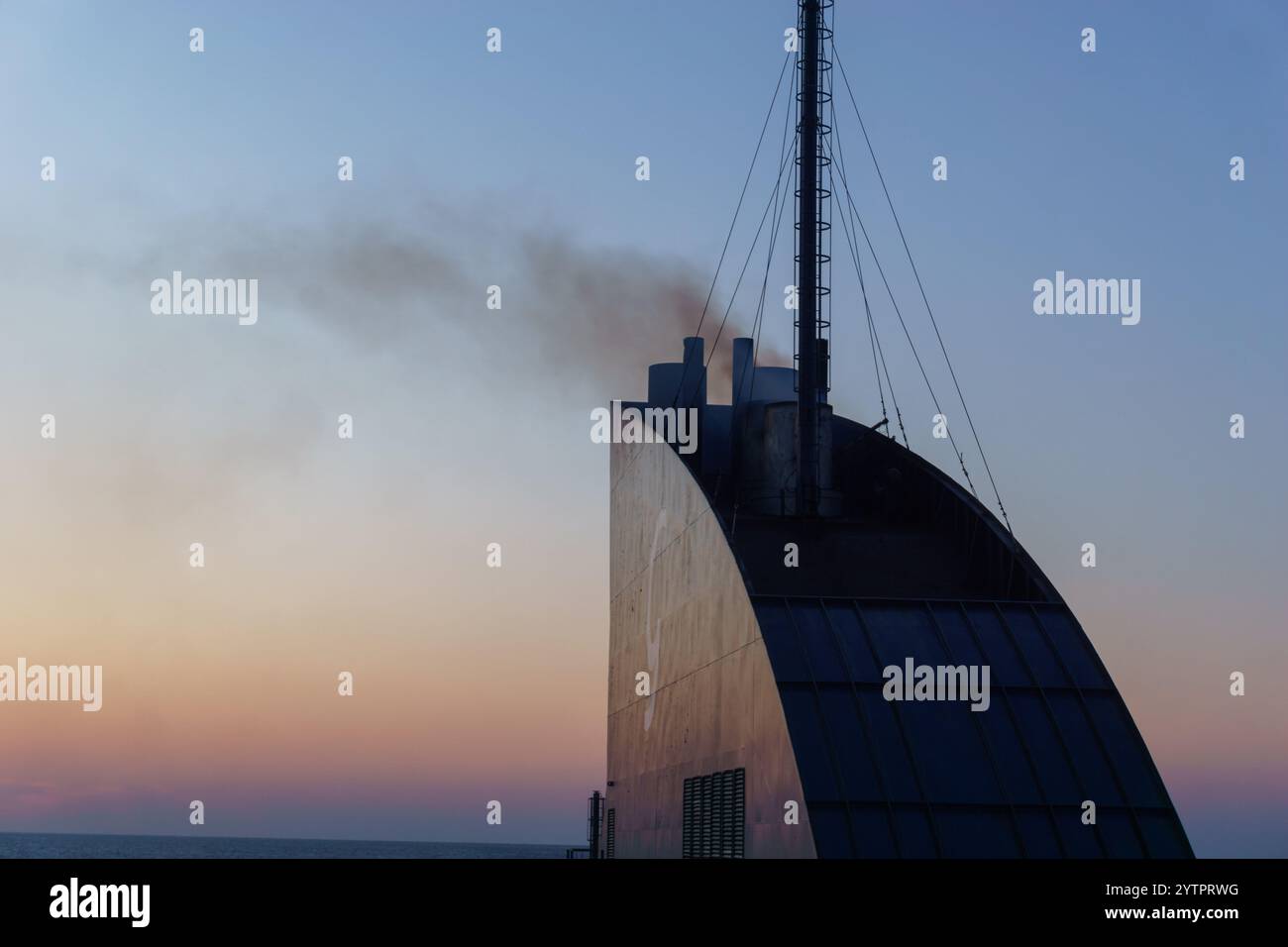 Ferry emitting black smoke out of exhaust on sea during evening ...