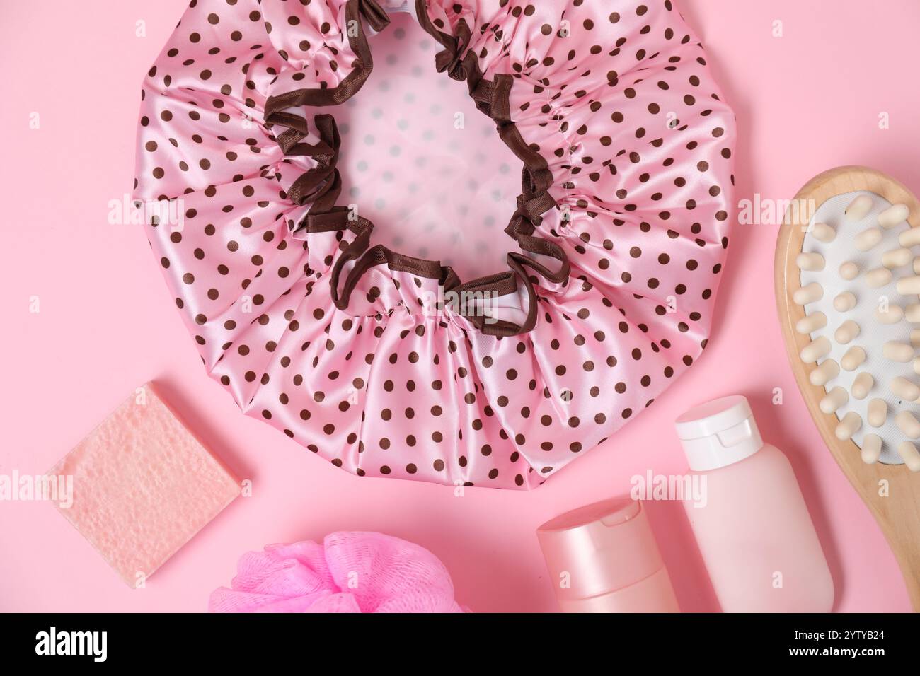 Shower cap and bath accessories on pink background, flat lay Stock Photo