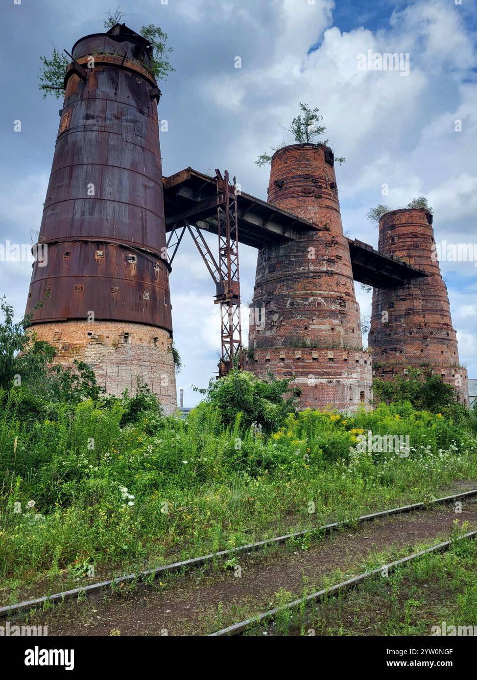 Abandoned Industrial Towers Surrounded By Nature Under Blue Sky - Smartphone Captured Stock Image