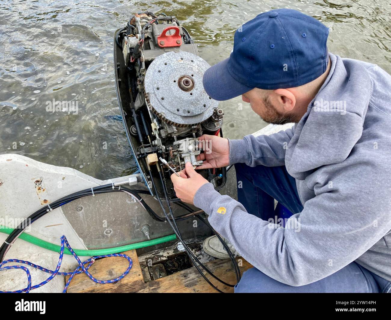 A man with a basecamp repairing a boat engine - Smartphone Captured Stock Image