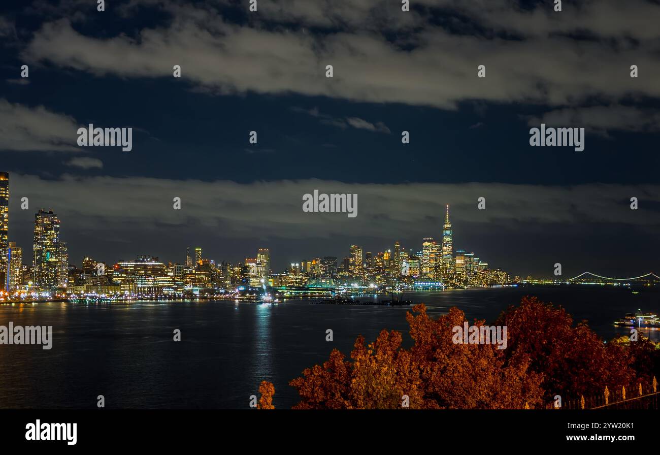 New York City Manhattan midtown skyline at night with lights reflection over Hudson River viewed from New Jersey Weehawken waterfront. Stock Photo